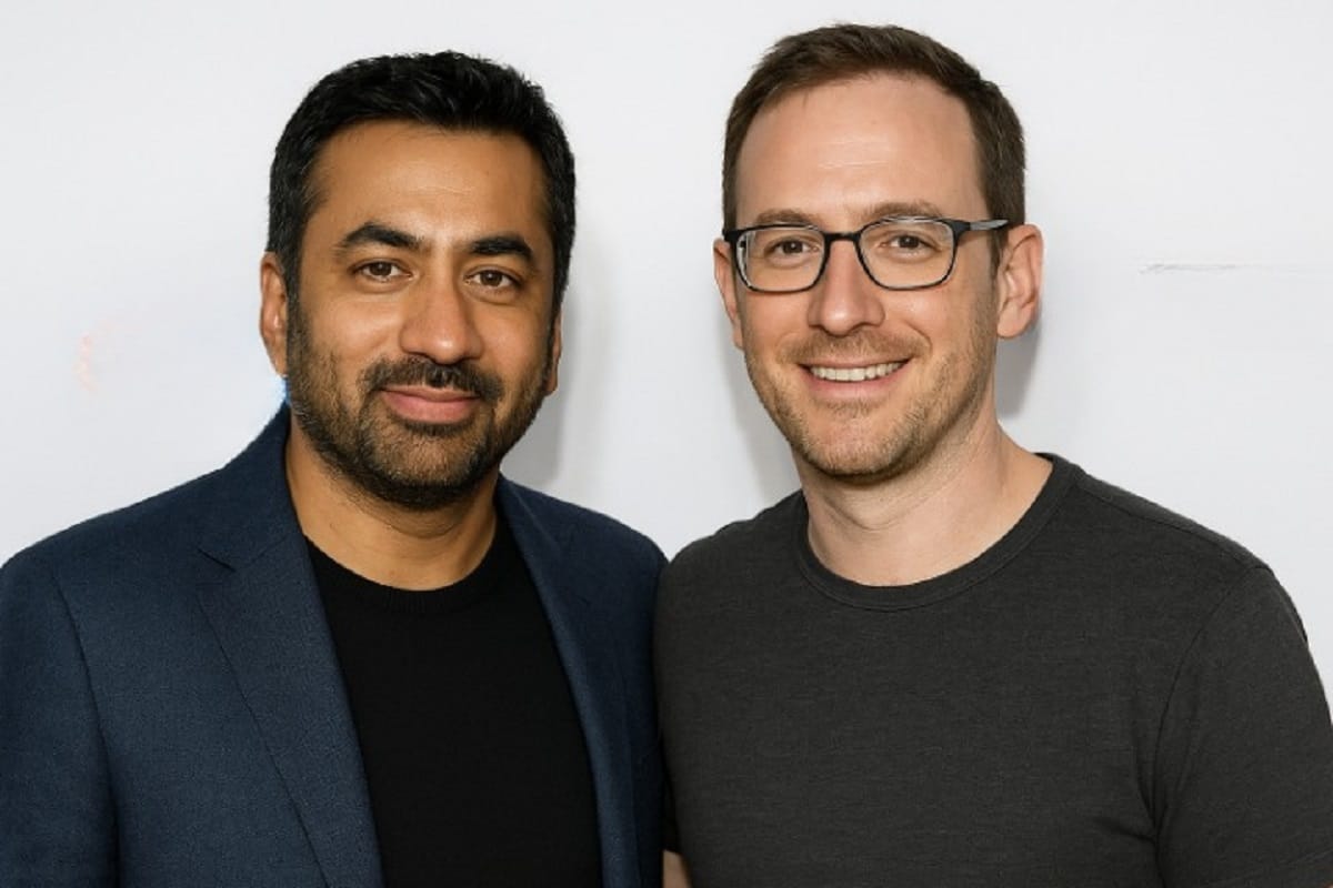 Actor Kal Penn and his partner Josh smile warmly together at a public event, posing side by side in casual attire against a simple entertainment backdrop.