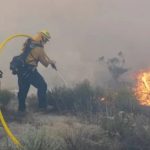Large plumes of thick white and gray smoke rise from a hillside wildfire during the Tusil Fire in San Diego County