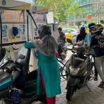 A person refilling a vehicle at a petrol pump in New Delhi showing the India fuel price hike on the digital meter.