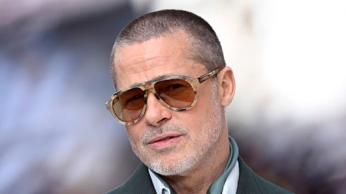 Brad Pitt looking thoughtful during a 2026 interview alongside Knox Jolie debuting a red spiky hairstyle in Los Angeles.