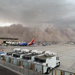 A massive, towering wall of brown dust swallowing high-rise buildings and highways in Phoenix Arizona during a severe monsoon storm.